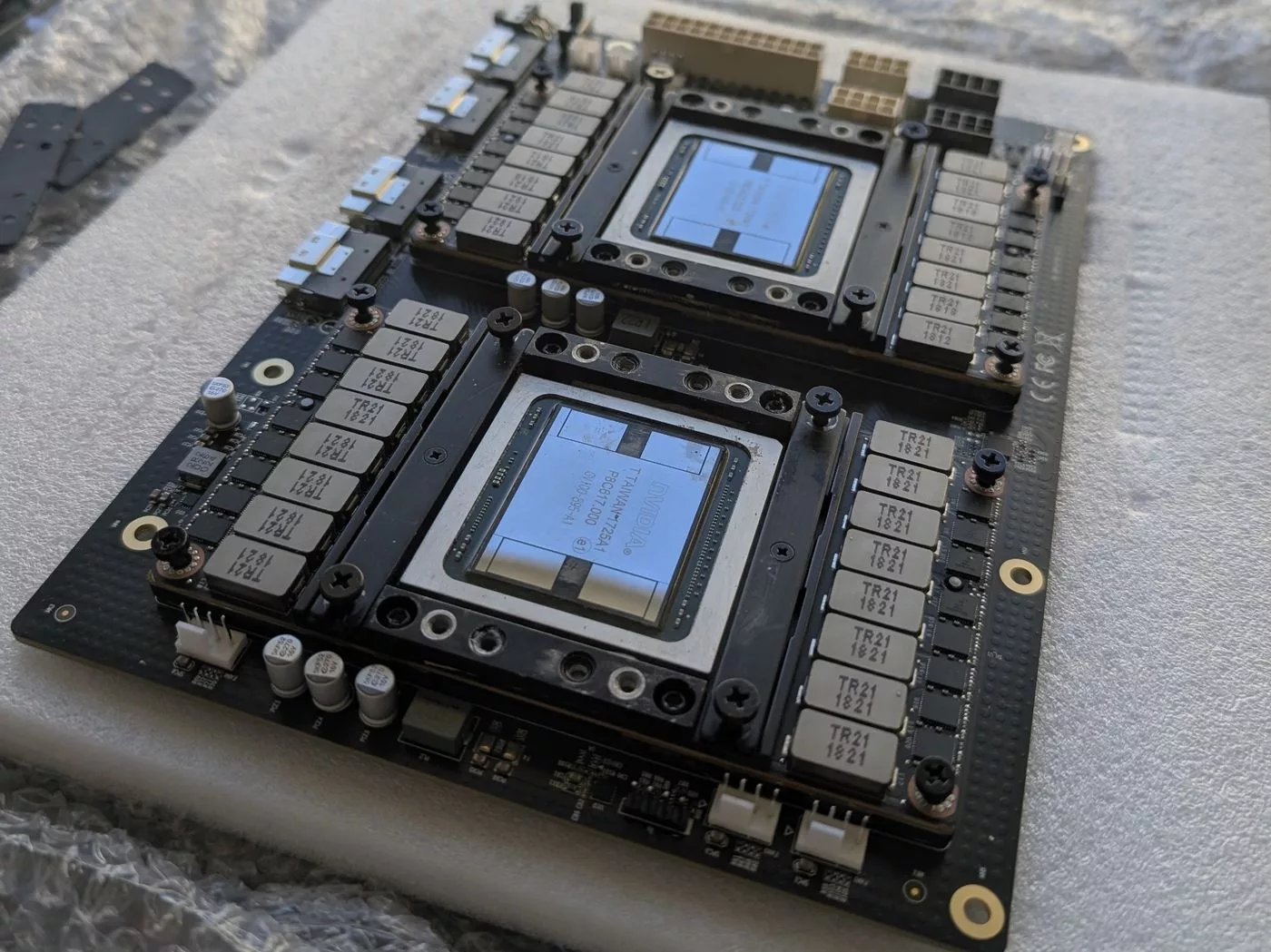 A carrier board with two V100 modules resting on foam and bubble wrap outdoors