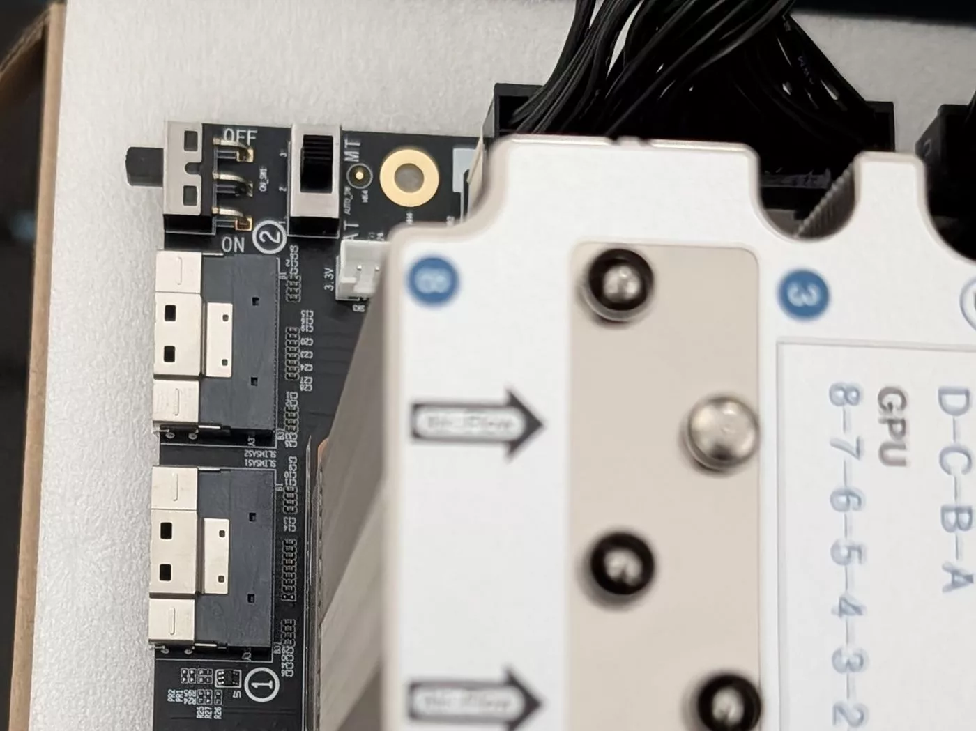 Close-up of a carrier board corner with a small power switch and four SFF-8654 cable ports beside a heatsink