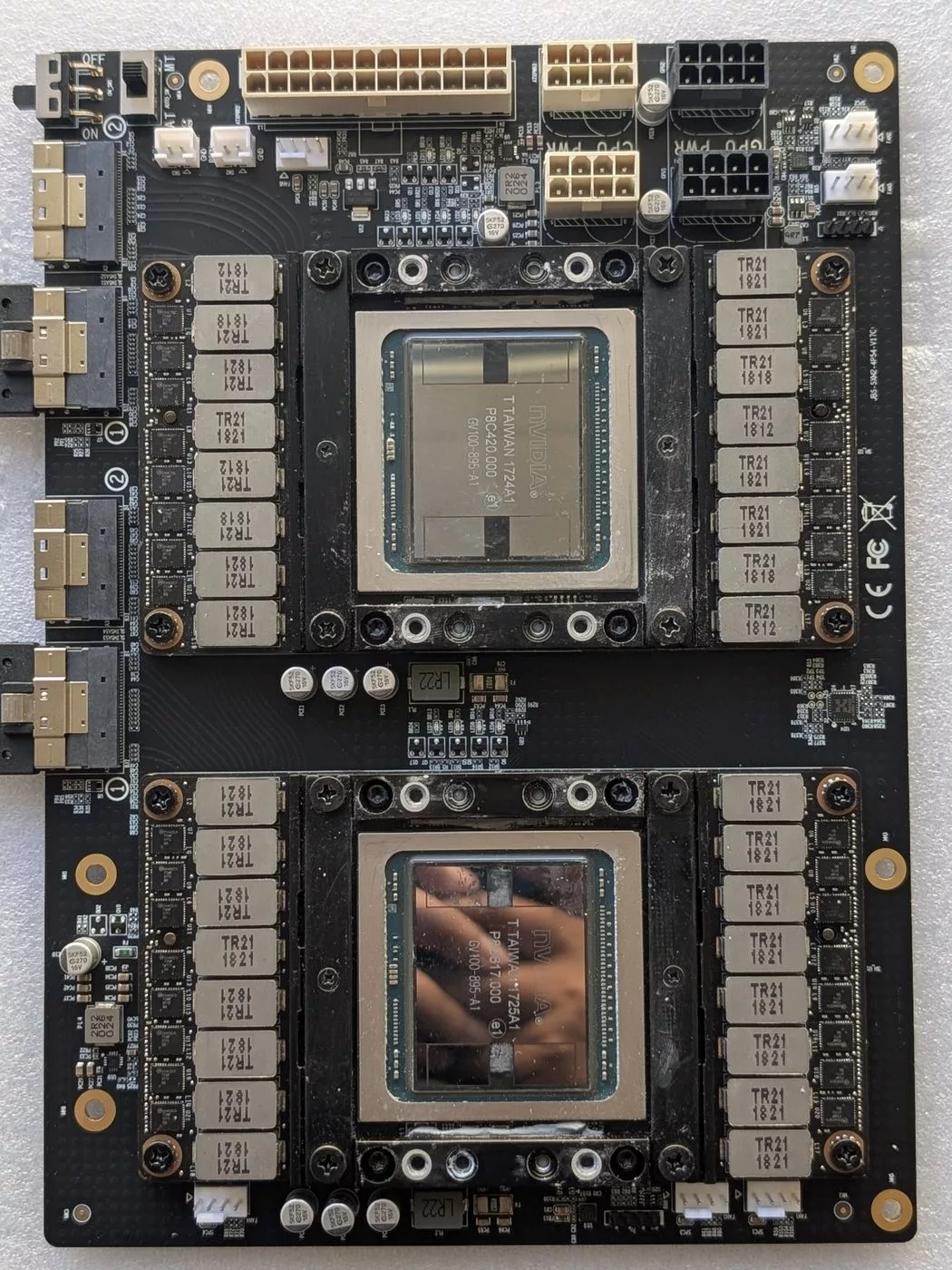 A carrier board holding two V100 modules, with blue SFF-8654 cables attached on the left