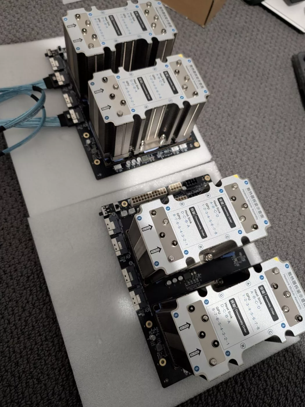 Two carrier boards with four large tower heatsinks installed, cables attached